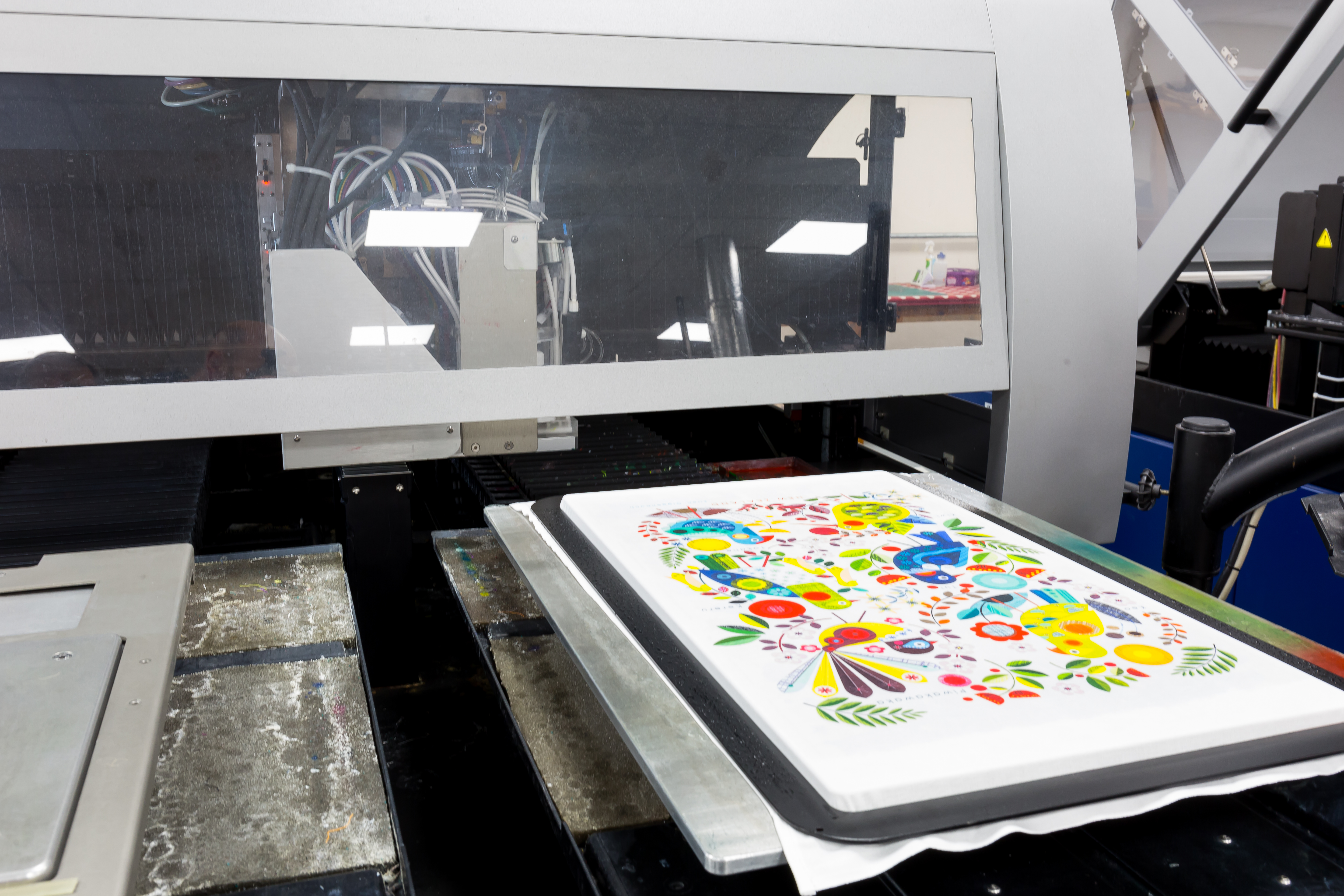 Brightly coloured tea towel waiting to be lifted off the print bed of a digital print machine.