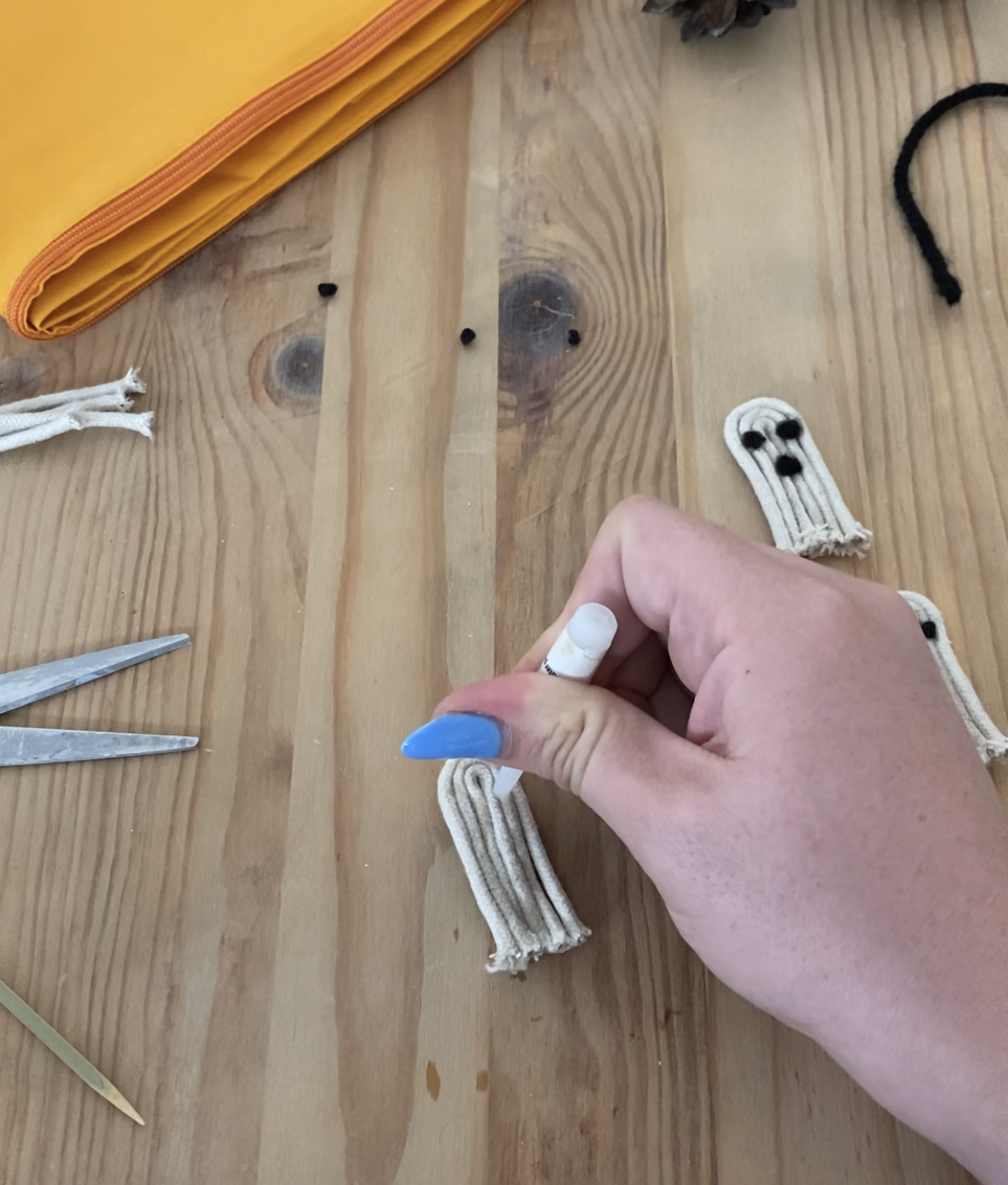 apply super glue to the front of the "ghost" and place the black rolled wool onto the glued area, hold with cocktail stick until stuck