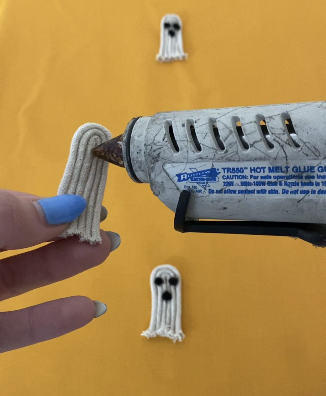 using a glue gun, apply glue to the reverse of the ghost and the place with pressure onto the cushion cover