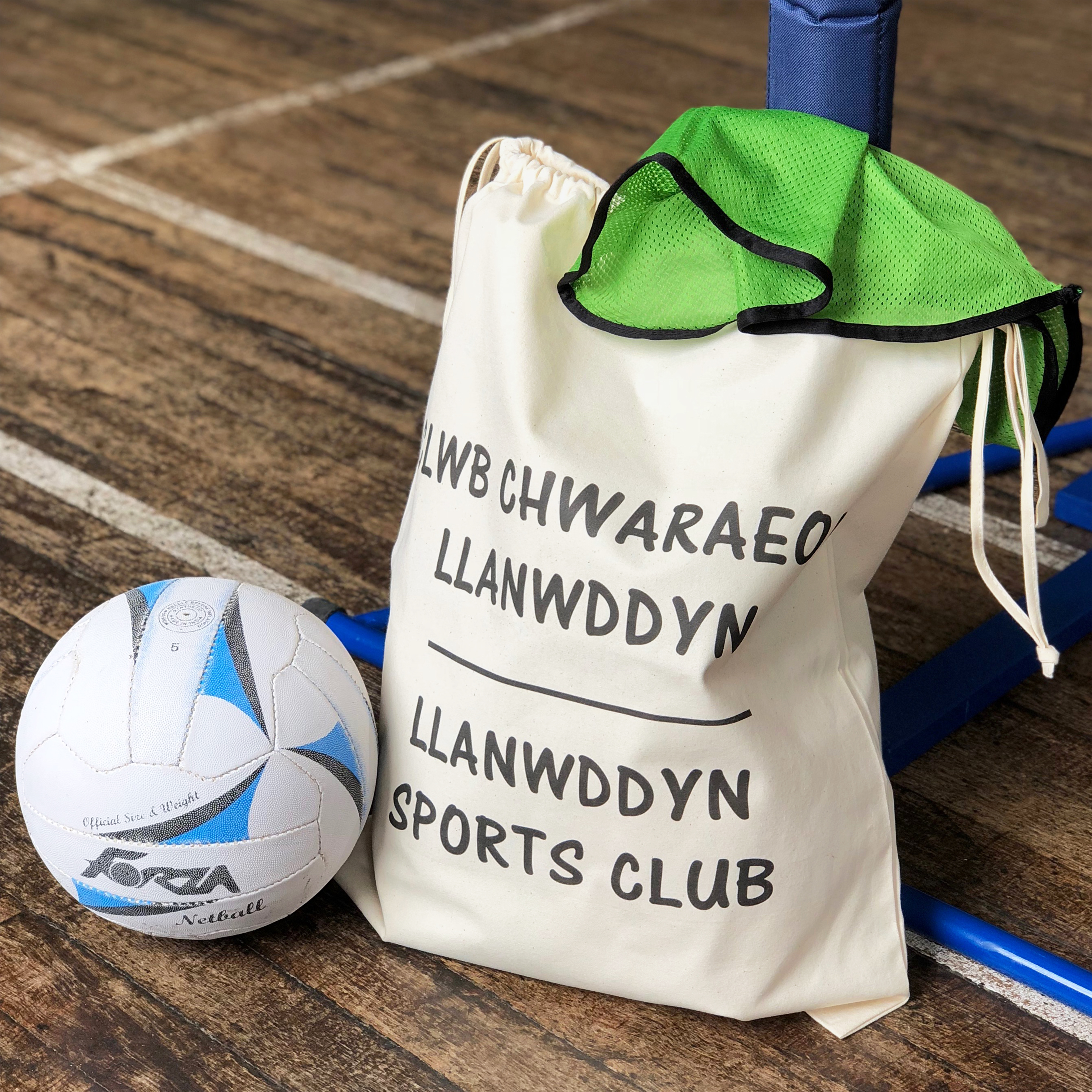 Large beige cotton sack with two drawcords which can close the bag at the top as well as a carrying handle, printed with the name of a village sports club.